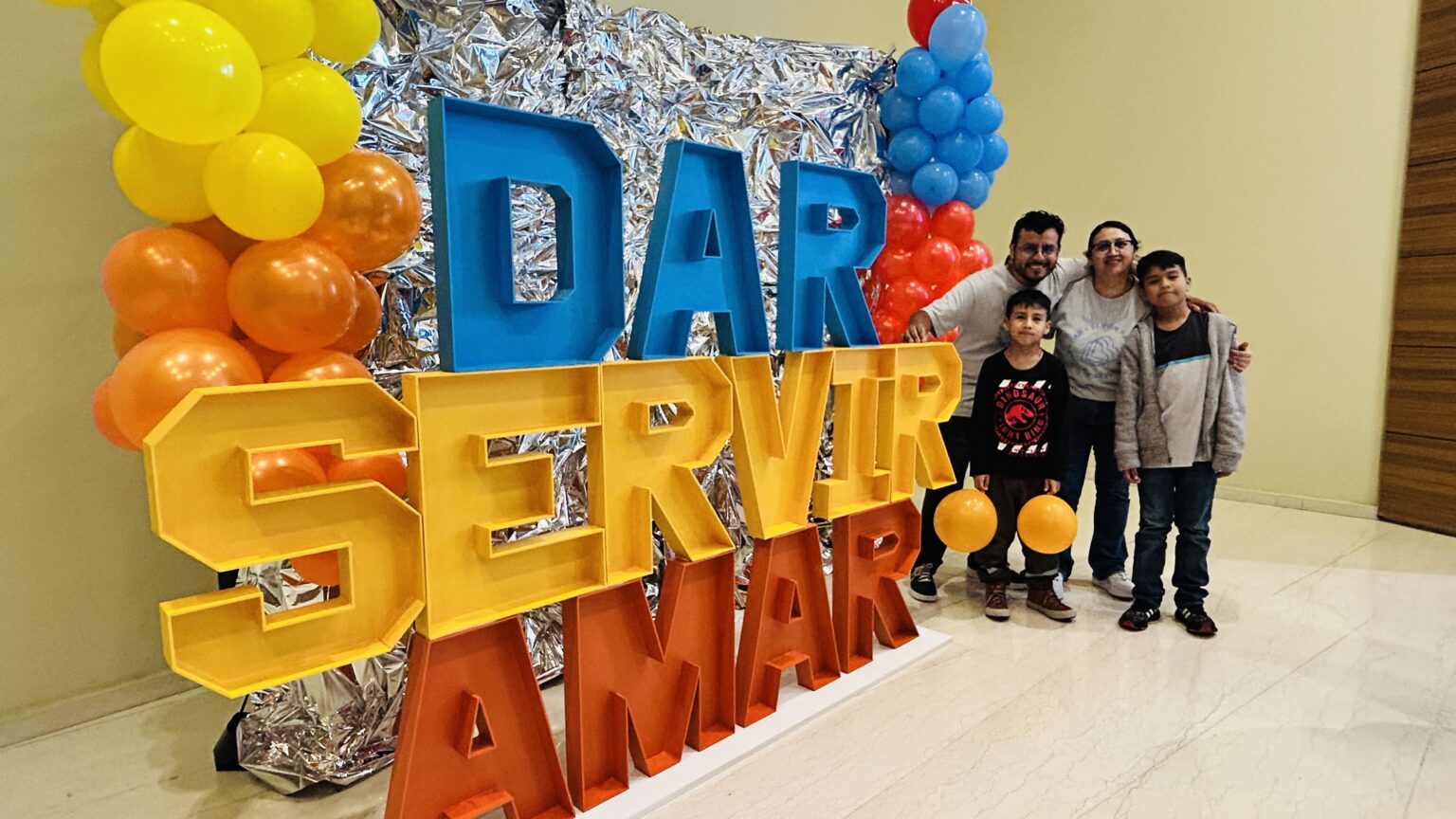 A family posing in front of the letters give, serve, love