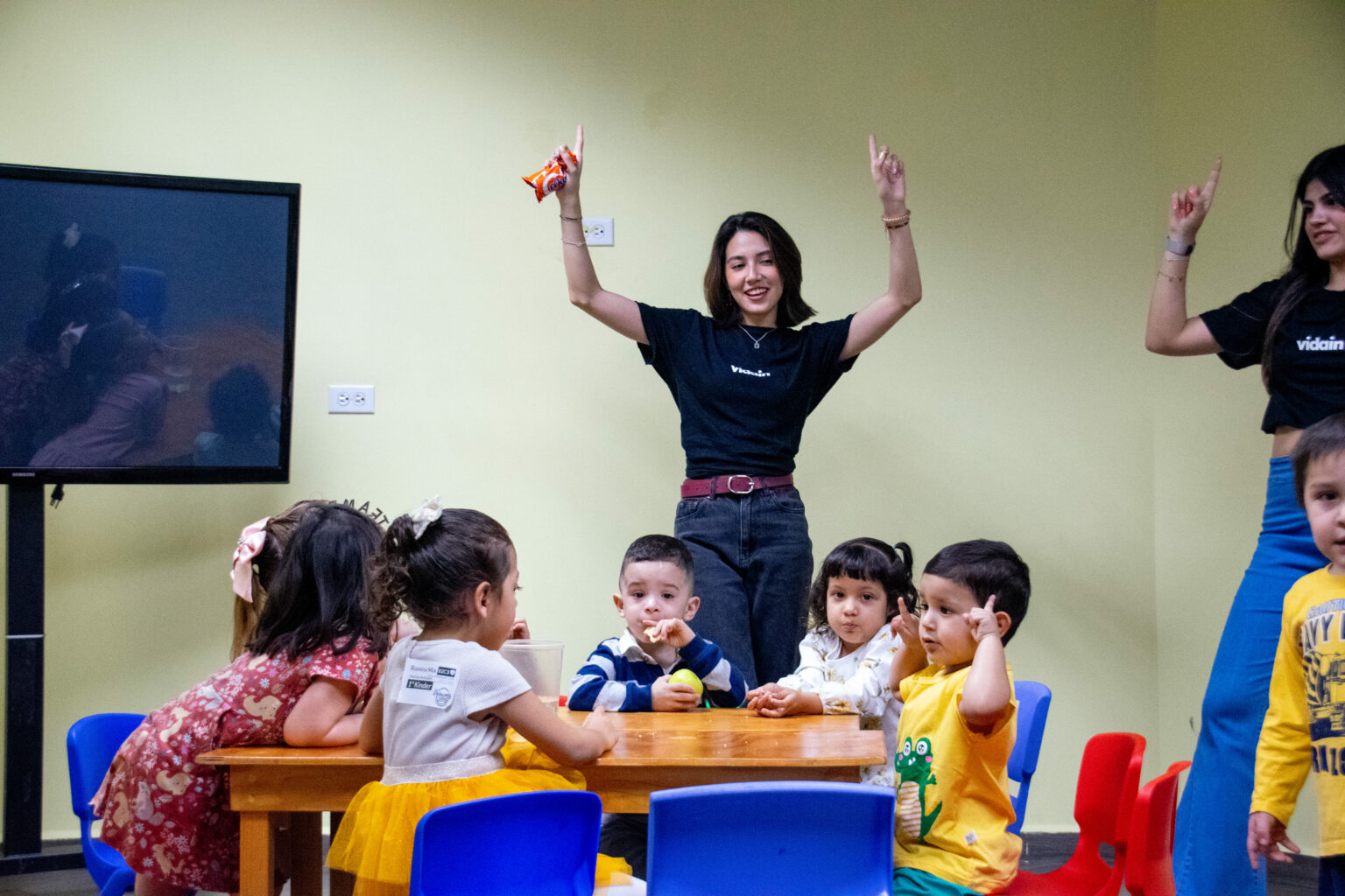 A volunteer raising her hands next to a group of kids