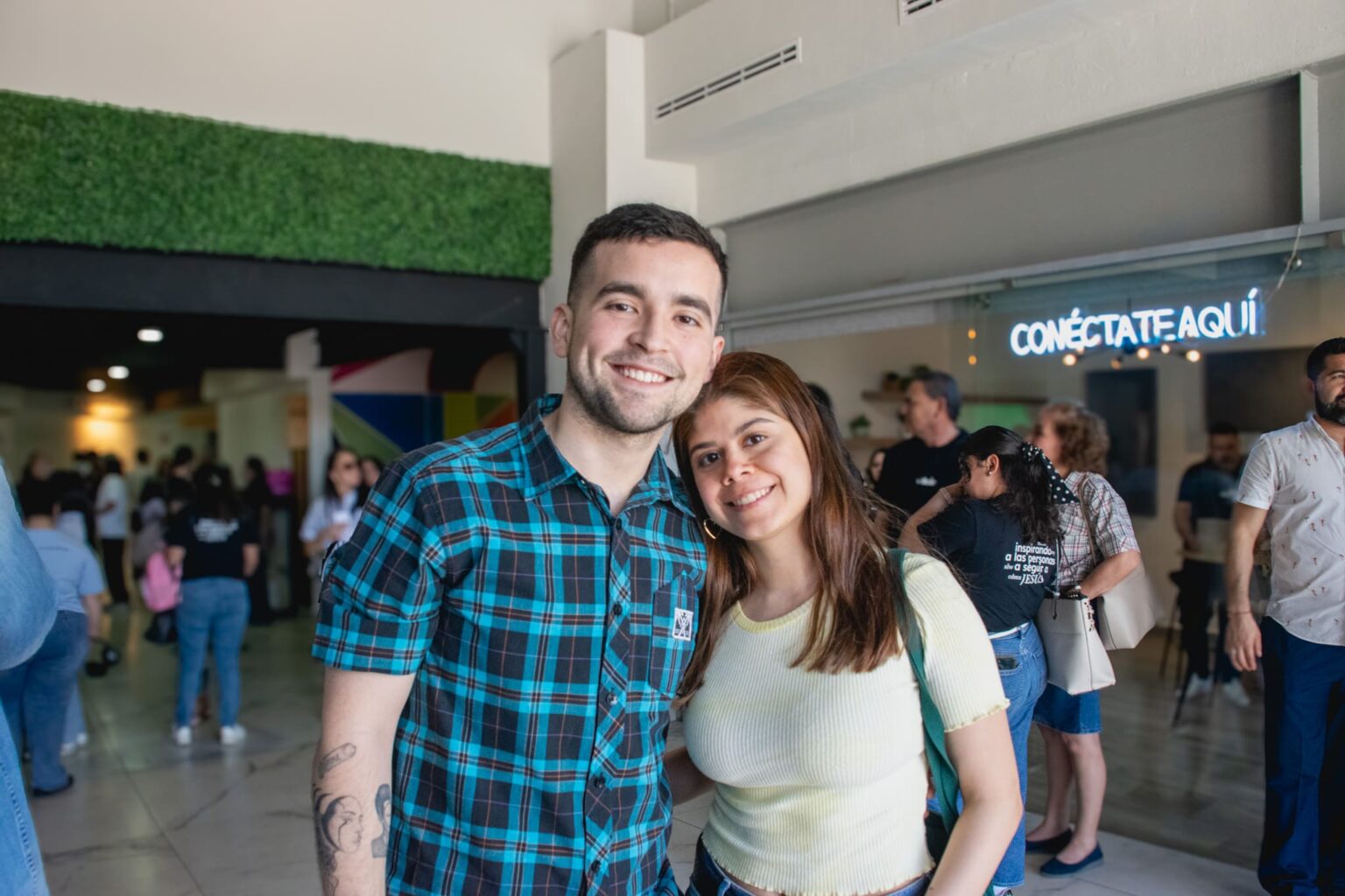 Two attendees smiling in the lobby, next to the connect here sign