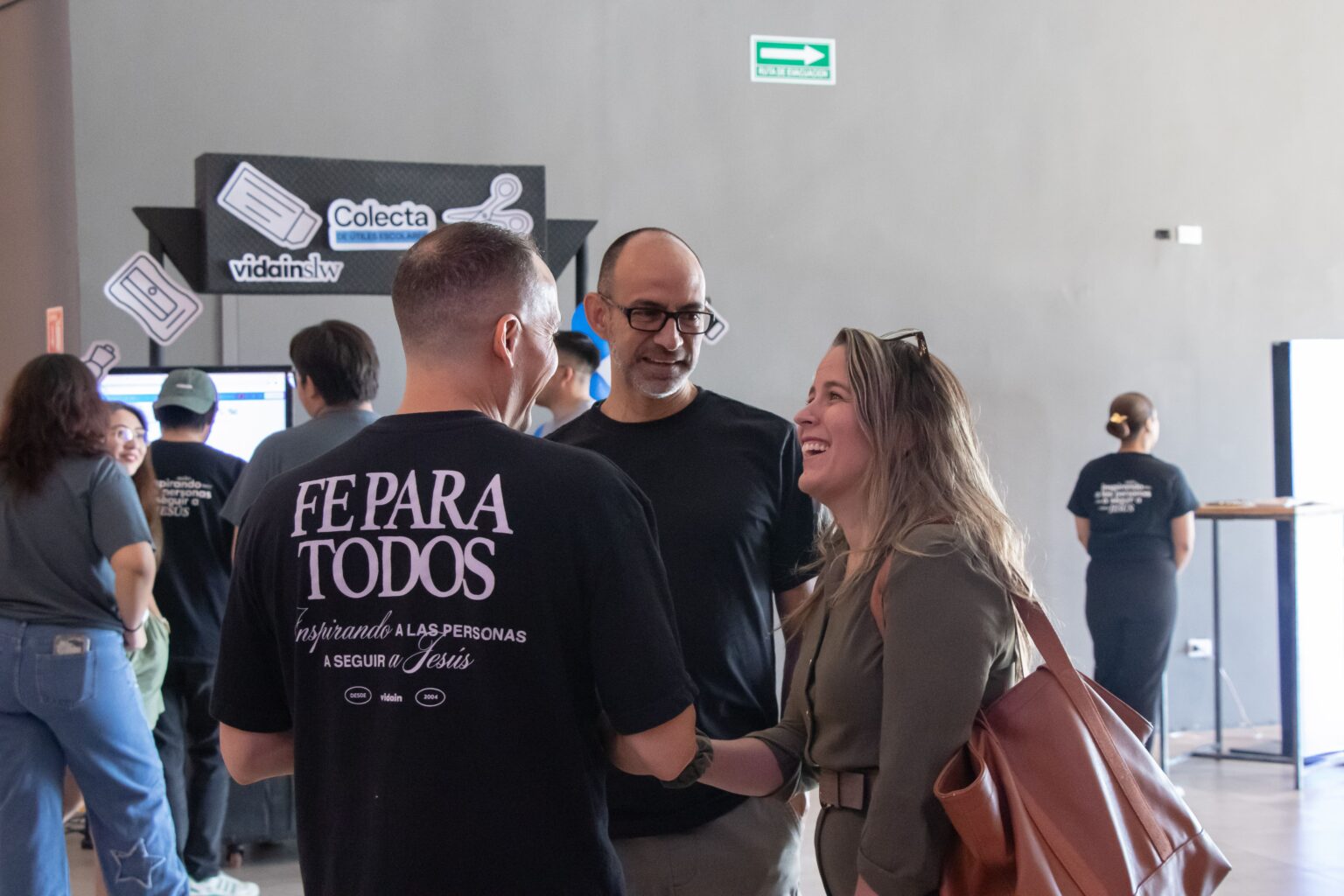 People talking; one is wearing a T-shirt that says faith for everyone