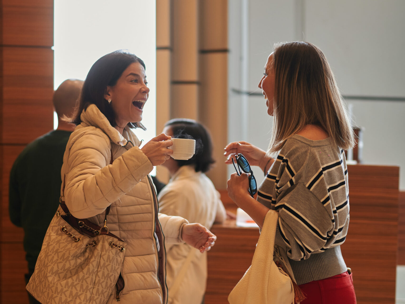 Two women greeting each other happily at a campus entrance