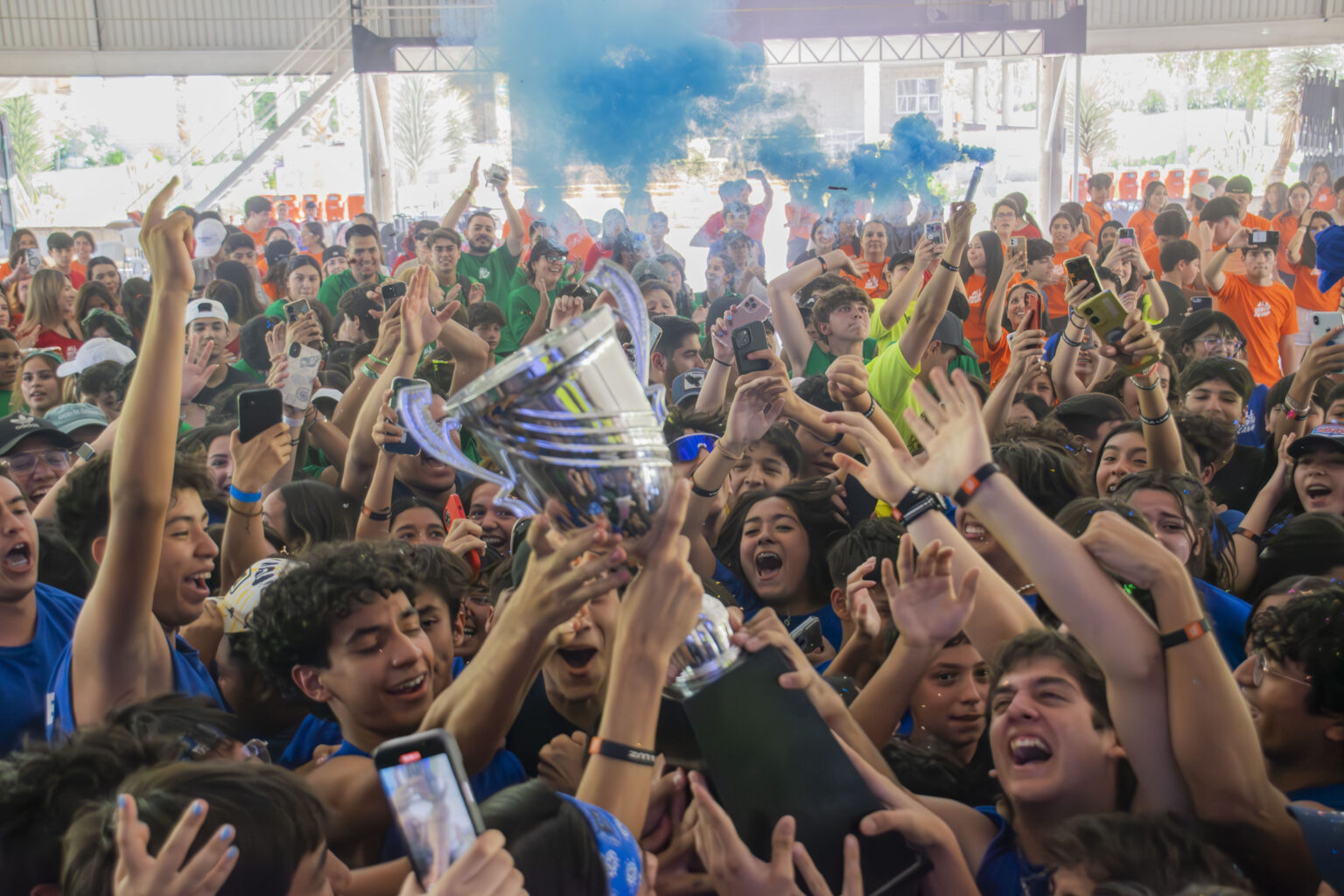 A crowd of young people celebrating with their phones in the air