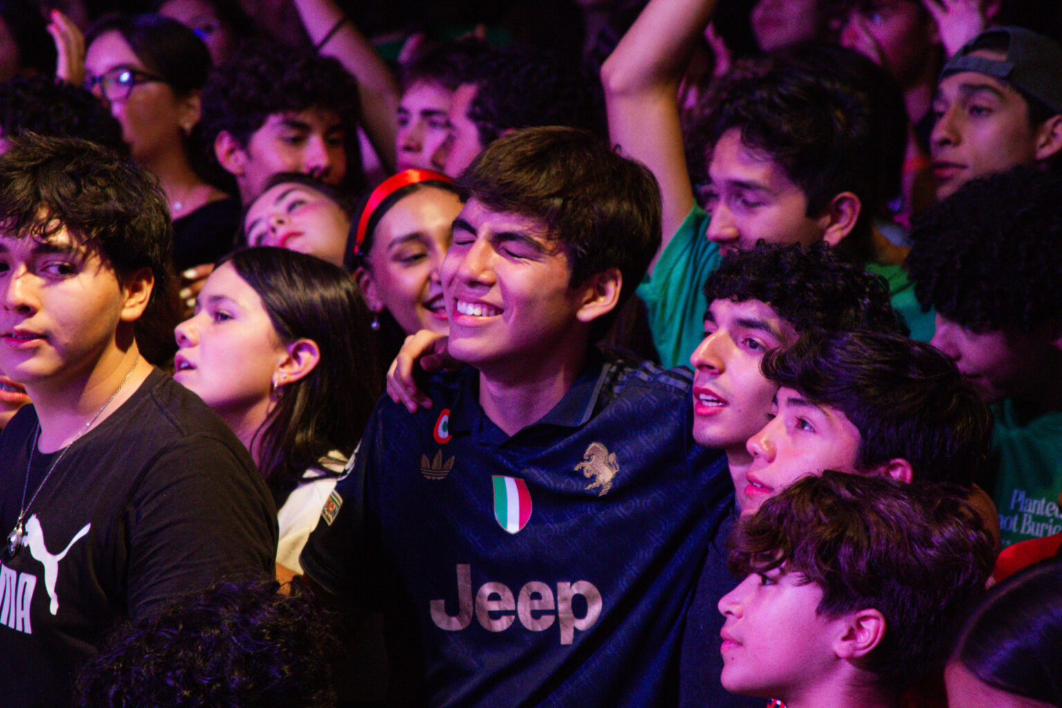 Young people smiling in the crowd during a night at All Youth Camp